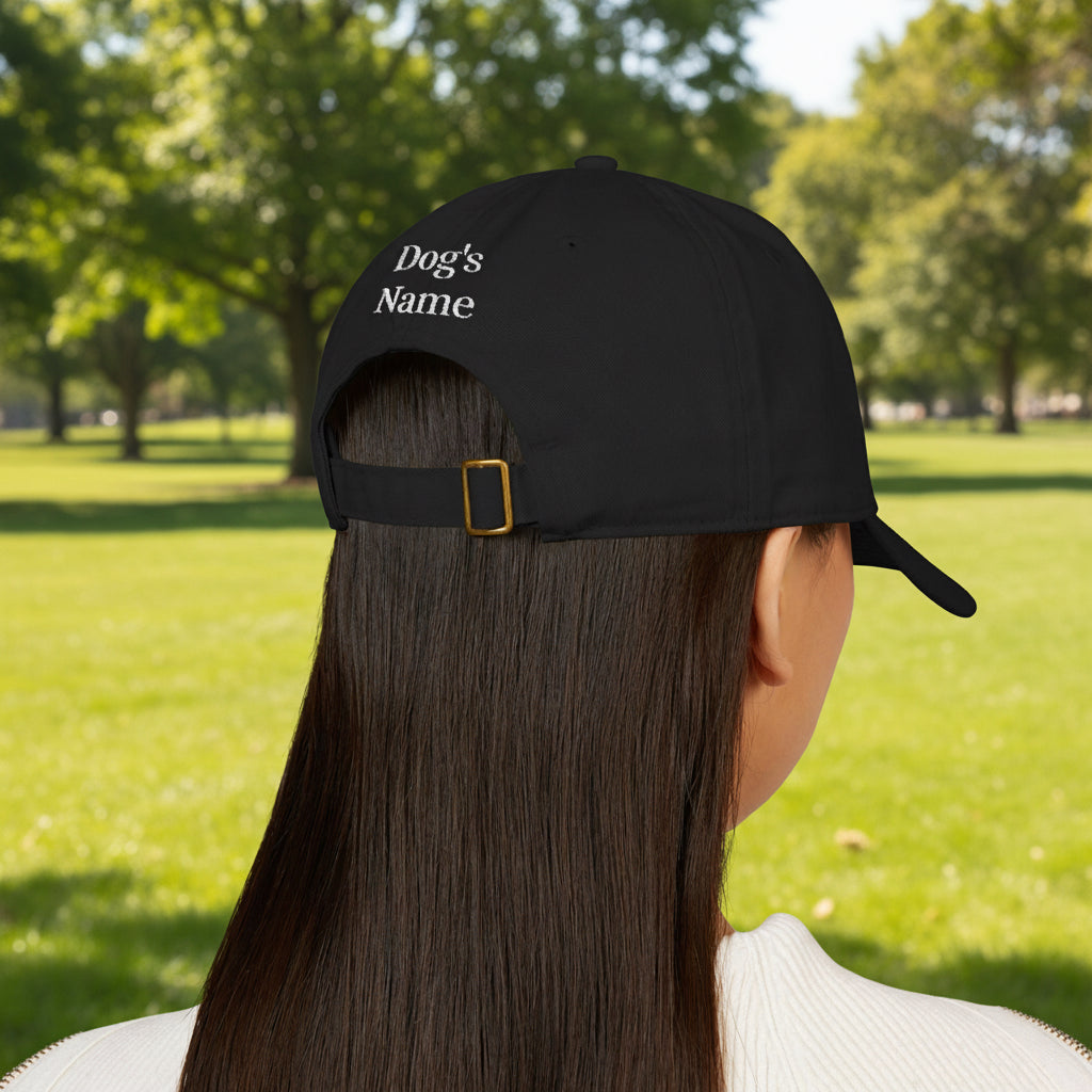 Black cap with 'Dog's Name' text worn by a person on a white background